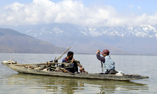 A man smokes hookah while another peddles boat in Wullar lake in Sopore on Wednesday. -Excelsior/ Aabid Nabi