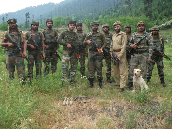 Army and police personnel pose with seized arms and ammunition in Handwara forests on Wednesday.