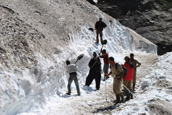 Labourers clear snow from road near holy cave shrine of Amarnath ji on Friday. —Excelsior/Sajad Dar