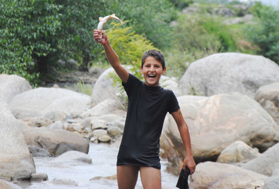 A boy enjoys fish hunt in Neeru river of Bhaderwah. (UNI)