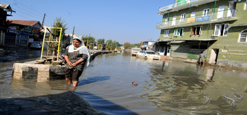A woman walks in Jawahar Nagar locality of Srinagar on Sunday, which is still waterlogged. —Excelsior/Amin War