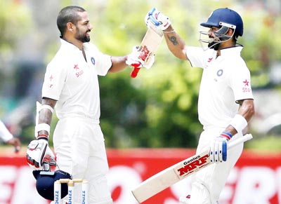 Shikhar Dhawan (L) celebrates his century with team captain Virat Kohli during the second day of first test cricket match against Sri Lanka in Galle on Thursday.(UNI)