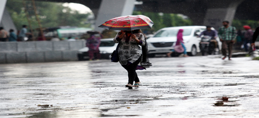A woman walks amidst rains and dark clouds in Jammu on Wednesday. — Excelsior/Rakesh