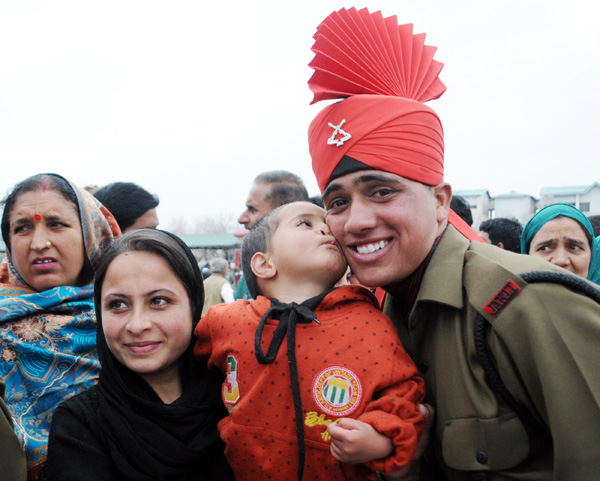 A new recruit of the Jammu Kashmir Light Infantry Regiment (JKLIR) poses for a photograph with his family after passing out parade at an Army base on the outskirts of Srinagar, on Saturday. —Excelsior Photo