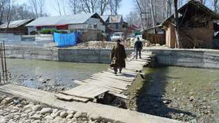 In absence of concrete bridge, people crossing over a wooden bridge constructed by themselves at Mugalpora in Pulwama district. -Excelsior/ Younis Khaliq In absence of concrete bridge, people crossing over a wooden bridge constructed by themselves at Mugalpora in Pulwama district. -Excelsior/ Younis Khaliq