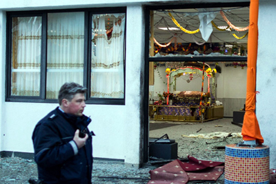 A police officers stand passes by a Gurudwara after three people have been injured in an apparently deliberate explosion.