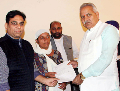PHE Minister, Sham Lal Choudhary distributing financial assistance to shelling hit person at R S Pura on Friday.