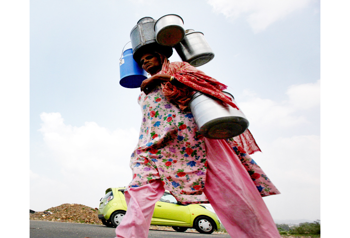 A woman carrying milk containers heads towards Jammu City on Saturday. —Excelsior/Rakesh