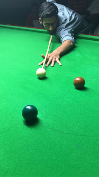 Cueist aiming at target during a match at Billiards Hall, MA Stadium in Jammu.