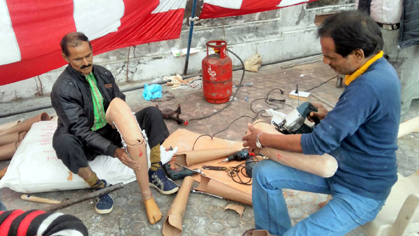A technician fabricating an artificial limb (right) and a physically challanged man wearing an artificial limb (left) during a camp at Jammu.