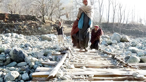 Residents of Gutroo village cross temporary wooden bridge over Bradi-Angan stream in Tral. —Excelsior/ Younis Khaliq