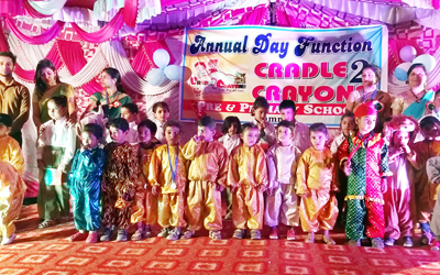 Children in colourful attires posing for a group photograph at Cradle 2 Crayons School in Jammu.