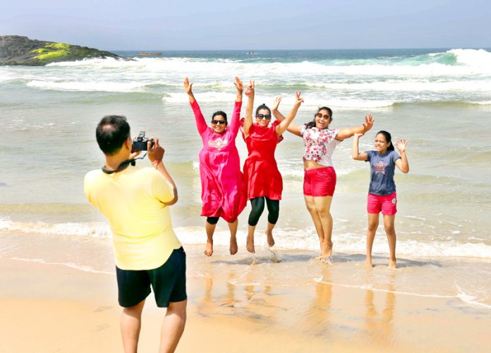 A group of tourists enjoying themselves at Kovalam beach in Thiruvananthapuram on Friday. (UNI)