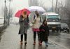 People walk amid fresh snowfall in Srinagar on Thursday. -Excelsior/Shakeel