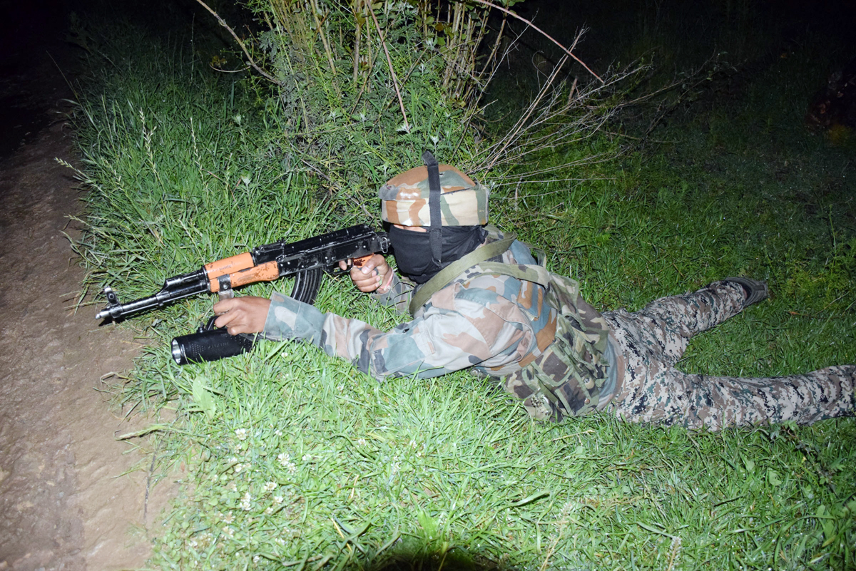 An Army jawan takes position at the site of encounter in Tral on Thursday evening. —Excelsior/Younis Khaliq