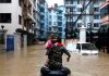 A member of Nepalese army carrying a child walks along the flooded colony in Kathmandu, Nepal