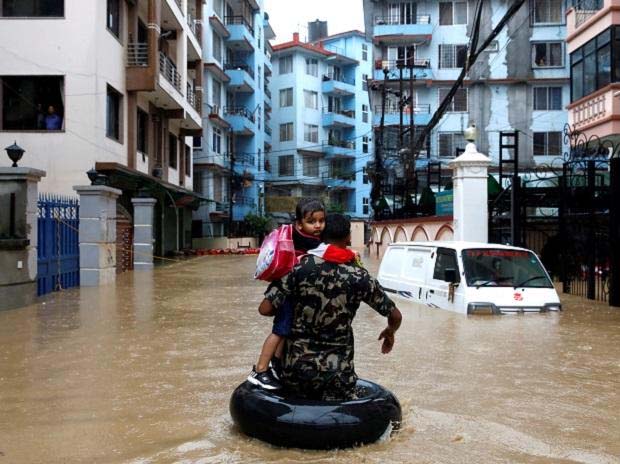 A member of Nepalese army carrying a child walks along the flooded colony in Kathmandu, Nepal