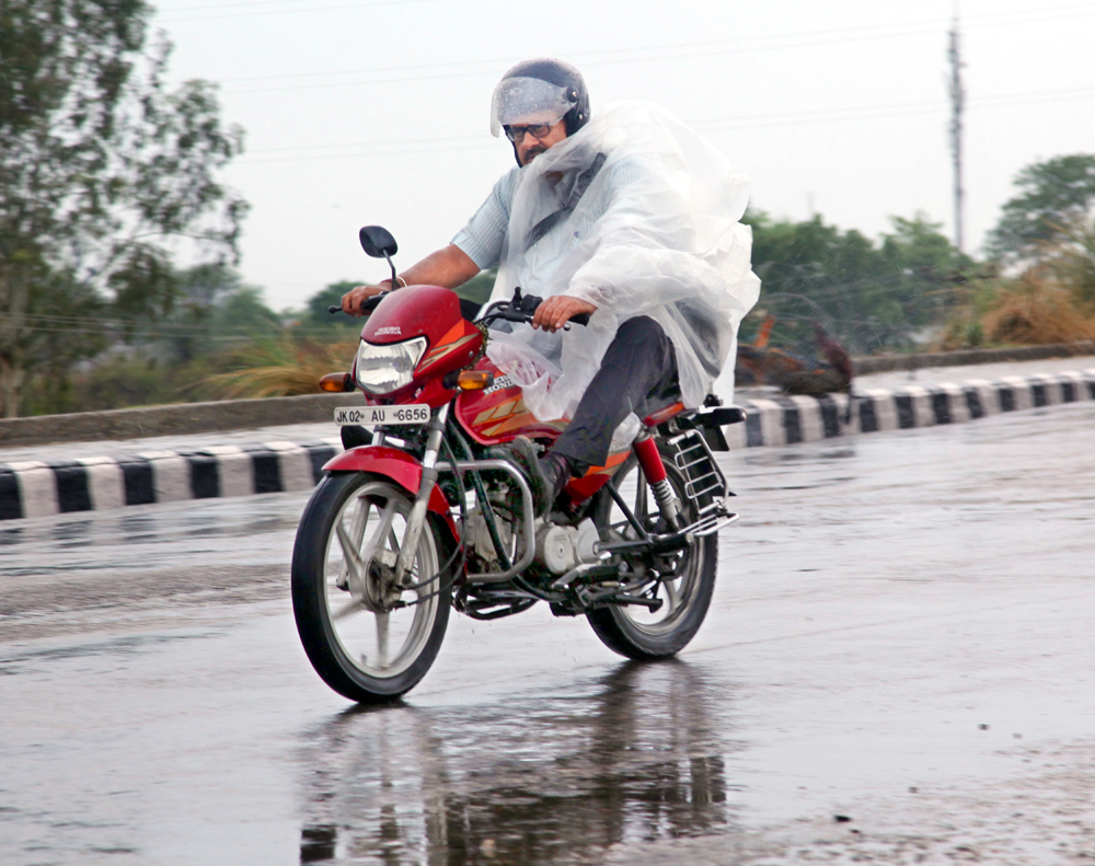 A bike rider covers himself while driving during rains in Jammu on Tuesday morning. -Excelsior/Rakesh
