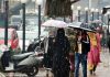 People take umbrella-cover as rain lashes Srinagar on Wednesday. Excelsior/Shakeel