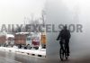 Trucks stranded on National Highway in Kashmir (left) and vehicles move with head-lights on at a Jammu road during dense fog on Tuesday morning (right).