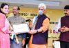 Lt Governor Manoj Sinha giving away Pride of Nation Excellence Award-2021 to a woman achiever in Delhi.