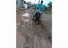 A biker balancing on muddy road to Sangam Vihar Colony Dandyal.
