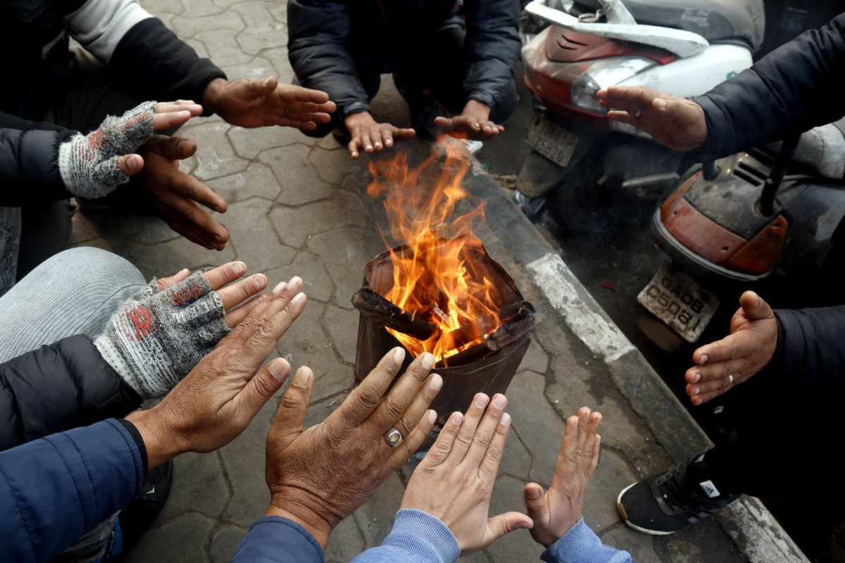 People warming themselves on roadside as mercury plummets across Kashmir. — Excelsior/Shakeel