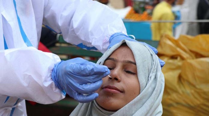 A Health worker collects nasal swab sample of a woman for COVID-19 test in Jammu on Thursday. (UNI)
