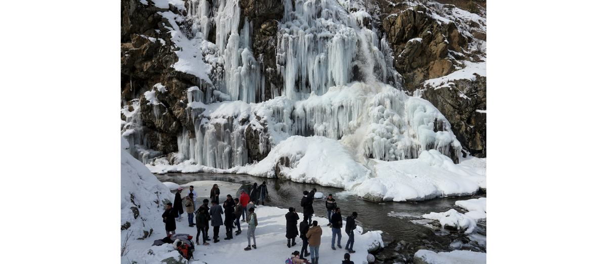 Visitors seen next to frozen waterfall during a cold winter day in Drung area of Tangmarg. -Excelsior/Aabid Nabi