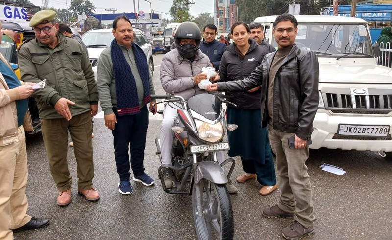 RTO Jammu and his team distributing helmet to a rider of two-wheeler on Saturday.