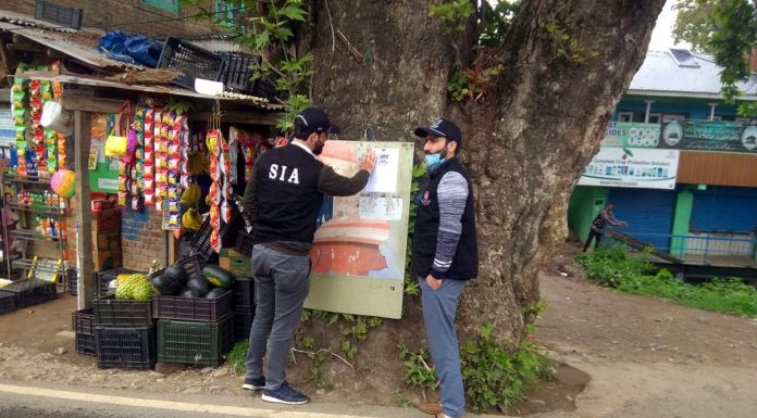 SIA personnel posting a notice outside a house after searches in Kashmir on Tuesday.