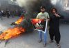 Supporters of former Prime Minister Imran Khan stand beside burning tyres as they block a road during a protest against his arrest in Hyderabad on Tuesday.