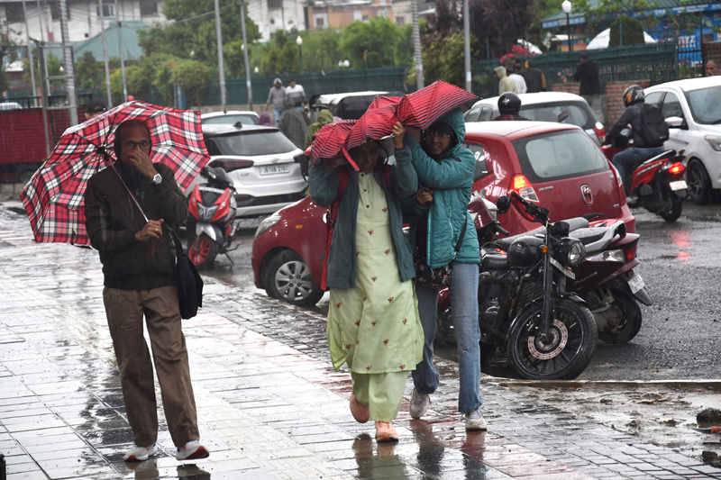 People walk during rain in Srinagar on Friday. — Excelsior/Shakeel