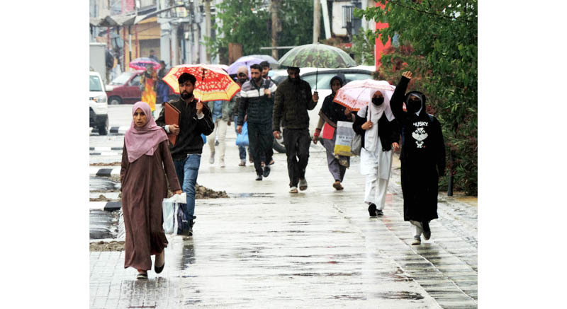 People take shelter under umbrellas during rain in Srinagar on Wednesday. (UNI)
