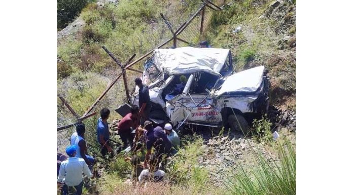 Rescuers stand near the vehicle that met with an accident in Ramban on Wednesday.