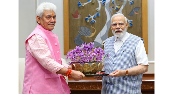 Lt Governor Manoj Sinha presenting saffron flowers to Prime Minister Narendra Modi in New Delhi on Tuesday. (UNI)