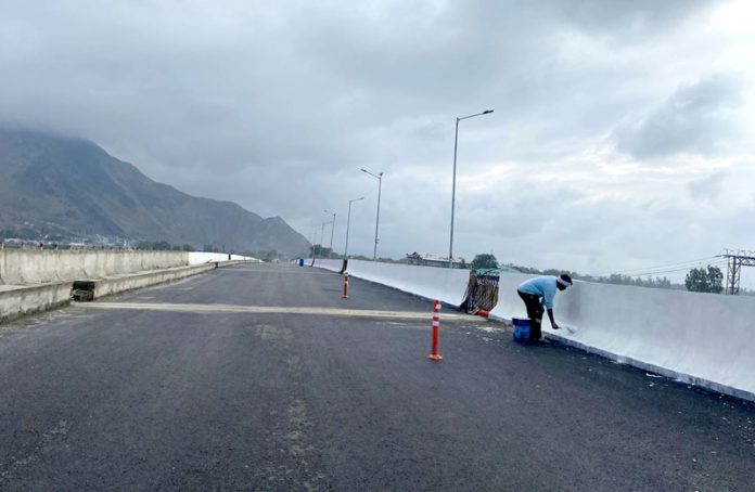 A worker painting sides of Lasjan flyover a day before it is opened to public on the outskirts of Srinagar on Wednesday. - Excelsior/Shakeel