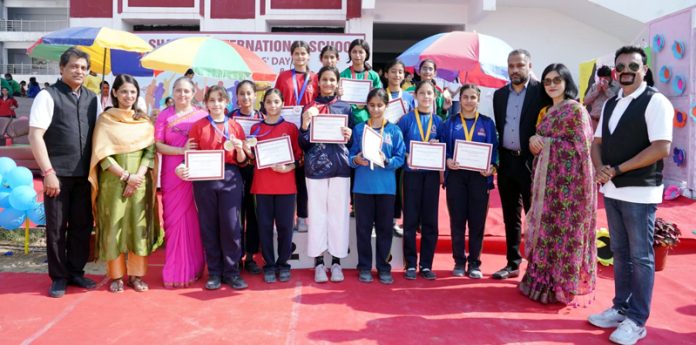 Students displaying certificates while posing with dignitaries during Annual Sports Day.