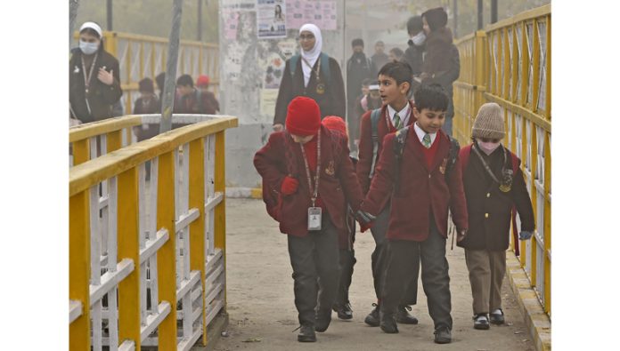 Children brave dense fog to reach schools in Srinagar on Tuesday. Excelsior/Shakeel