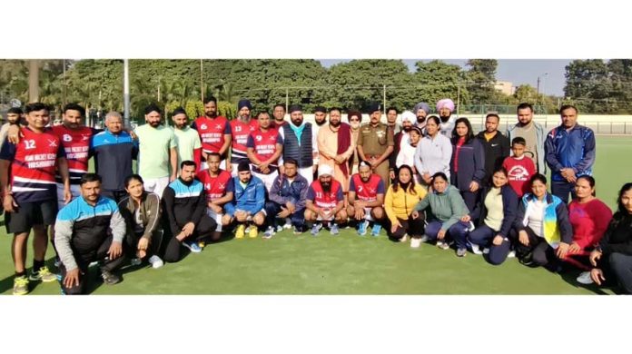 Dignitaries posing with hockey players during a tournament.