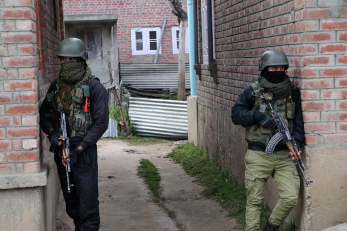 Security personnel take position near the encounter site in Hadigam area of Kulgam district on Thursday.