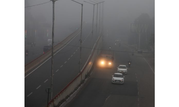 Vehicles with headlights on moving on a road through dense fog in Jammu on Thursday morning. -Excelsior/Rakesh