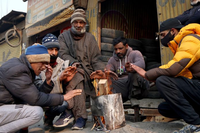 Amid bone-chilling minimum temperature, a group of people warming themselves on roadside in Srinagar on Friday morning. — Excelsior/Shakeel