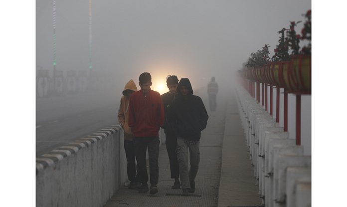 People walk amid dense fog on a cold morning in Jammu. -Excelsior/Rakesh