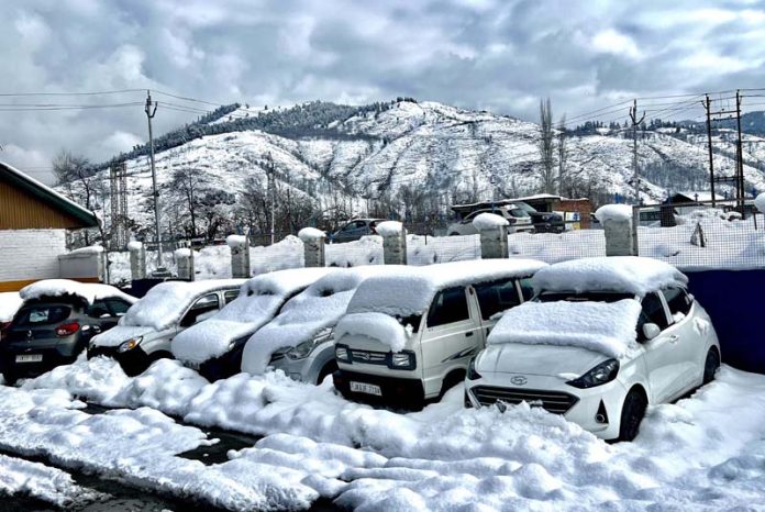 Parked vehicles covered with snow in Anantnag on Monday.