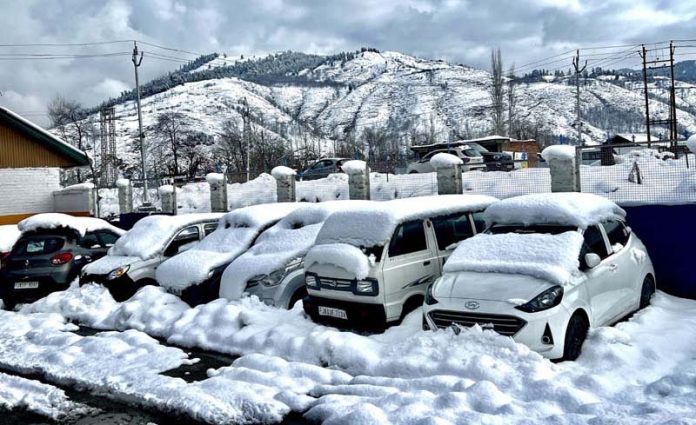 Parked vehicles covered with snow in Anantnag on Monday.