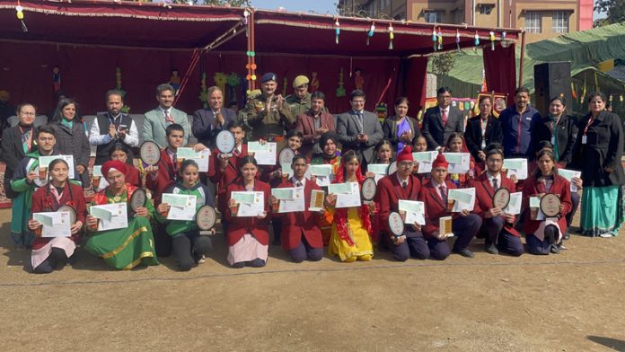 Students of RMPS displaying trophies and certificates while posing with dignitaries on Sports Day.