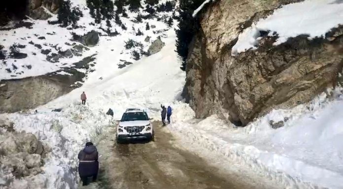 A vehicle passing through the Zojila Pass after it was opened on Monday. — Excelsior/Basharat Ladakhi