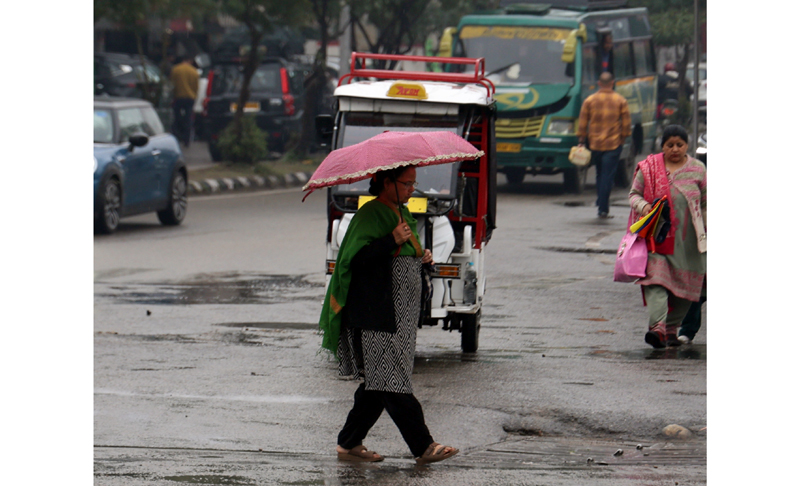 A woman moves on a Jammu road during rain on Friday.— Excelsior/Rakesh