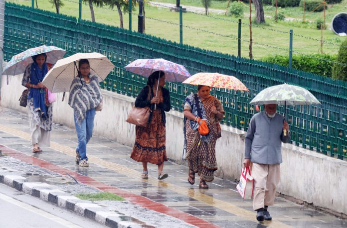 Tourist women walk with umbrellas in Srinagar on Thursday. -Excelsior/Shakeel
